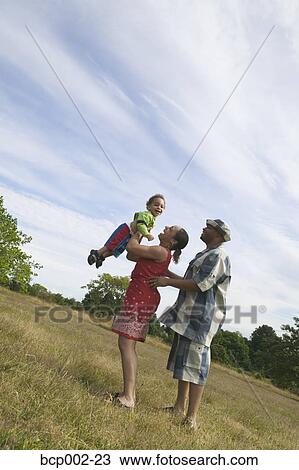 A couple playing with their son in grassy field. View Large Photo Image Stock Image - A couple playing with their son in grassy field. . Fotosearch