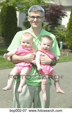 A father holding his two babies outdoors. View Large Photo Image Stock Photo - A father holding his two babies outdoors.. Fotosearch