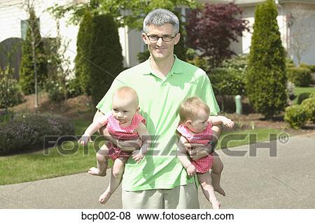 A father holding his two babies outdoors. View Large Photo Image Stock Photo - A father holding his two babies outdoors.. Fotosearch