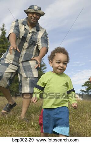 Stock Photo - A father playing with his toddler son outside.. Fotosearch
