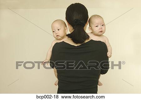 Stock Photo - A mother holding her twin babies.. Fotosearch