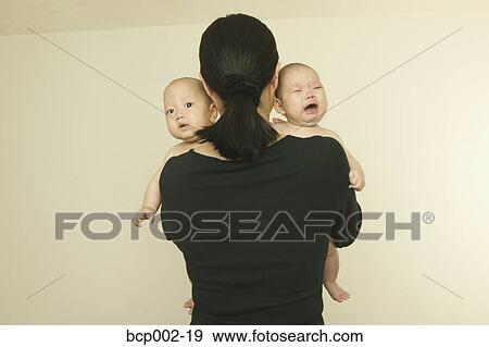 Stock Photo - A mother holding her twin babies.. Fotosearch