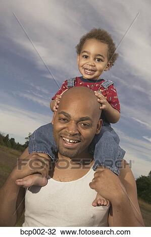 Stock Image - A toddler riding on his father's shoulders.. Fotosearch