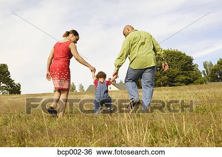 A toddler walking between his mother and father. View Large Photo Image Stock Photograph - A toddler walking between his mother and father. . Fotosearch