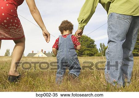 A toddler walking between his mother and father. View Large Photo Image Stock Photography - A toddler walking between his mother and father. . Fotosearch