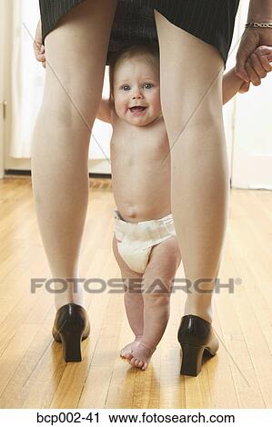 Stock Image - Baby peering out from between her mother's legs. . Fotosearch