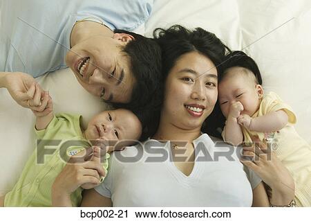 High angle portrait of a man and woman with their twin babies. View Large Photo Image Stock Image - High angle portrait of a man and woman with their twin babies. . Fotosearch