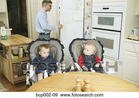 Stock Photo - Twin babies in high chairs.. Fotosearch
