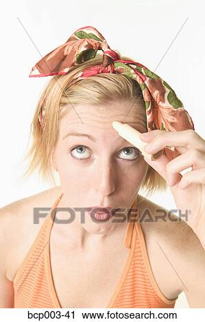 A woman applying concealer to a spot on her forehead. View Large Photo Image Stock Image - A woman applying concealer to a spot on her forehead.. Fotosearch