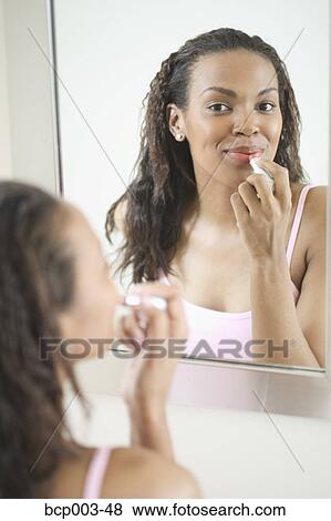 A woman applying lipstick in a mirror. View Large Photo Image Stock Photo - A woman applying lipstick in a mirror.. Fotosearch