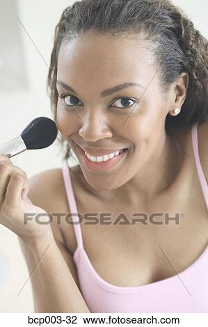 A woman applying make-up to her face. View Large Photo Image Stock Image - A woman applying make-up to her face.. Fotosearch