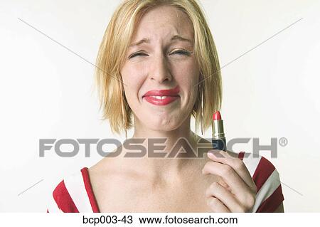 A woman holding up the lipstick she's just applied. View Large Photo Image Stock Image - A woman holding up the lipstick she's just applied.. Fotosearch