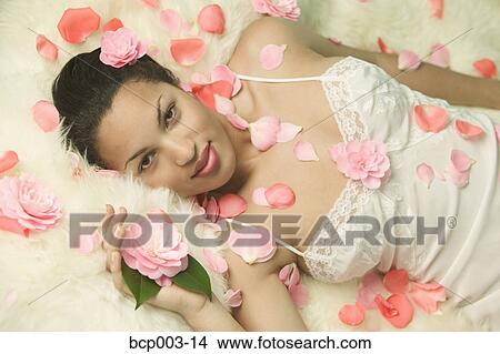 A woman resting on a bed strewn with flowers. View Large Photo Image Picture - A woman resting on a bed strewn with flowers.. Fotosearch