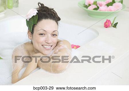 A woman smiling as she relaxes in a bathtub full of bubbles. View Large Photo Image Stock Photo - A woman smiling as she relaxes in a bathtub full of bubbles.. Fotosearch