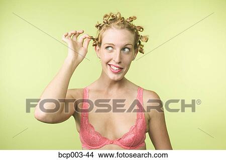 Picture - A woman twisting the curls in her hair.. Fotosearch