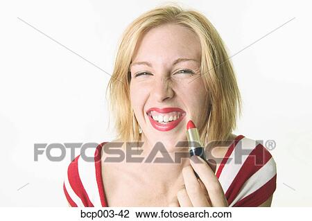 A young woman applying red lipstick. View Large Photo Image Stock Image - A young woman applying red lipstick.. Fotosearch