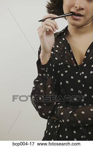 A young woman chewing on a pen. View Large Photo Image Stock Photo - A young woman chewing on a pen. . Fotosearch