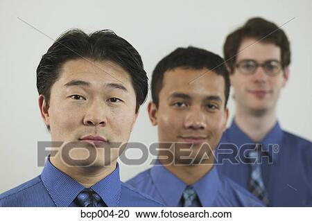 Stock Image - Studio portrait of three businessmen in blue shirts. . Fotosearch