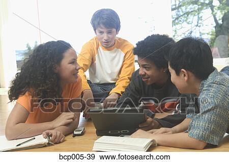 Four teenage kids working on a laptop and school books. View Large Photo Image Stock Photo - Four teenage kids working on a laptop and school books. . Fotosearch