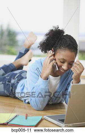 Teen girl working at a laptop computer and talking on the phone. View Large Photo Image Stock Image - Teen girl working at a laptop computer and talking on the phone. . Fotosearch
