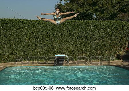 Teenage girl does the splits while jumping into a swimming pool. View Large Photo Image Stock Photograph - Teenage girl does the splits while jumping into a swimming pool. . Fotosearch