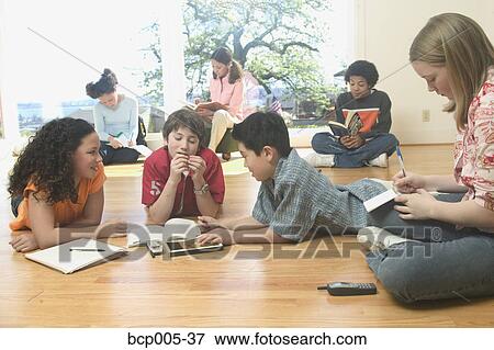 Teenage girls and boys lying on the floor and doing homework. View Large Photo Image Stock Photo - Teenage girls and boys lying on the floor and doing homework.. Fotosearch