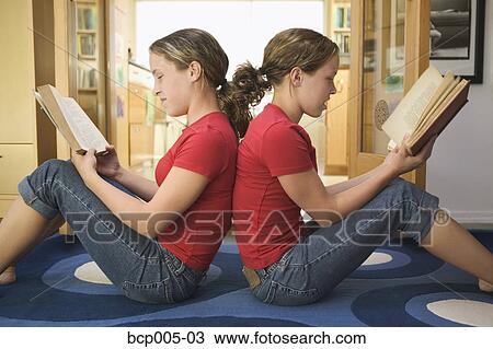 Teenage twin girls sit back to back while reading. View Large Photo Image Stock Image - Teenage twin girls sit back to back while reading. . Fotosearch