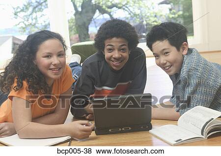 Stock Photo - Three teenage kids working on a laptop and school books. . Fotosearch