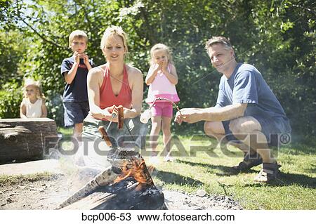 Stock Image - Family gathered around the campfire.. Fotosearch