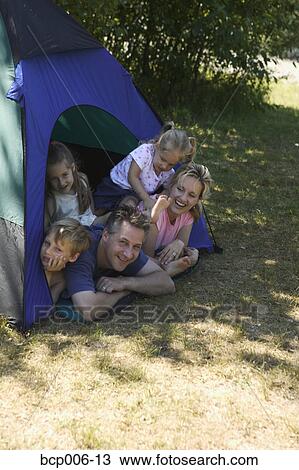 Stock Image - Family looking out of tent at campsite.. Fotosearch