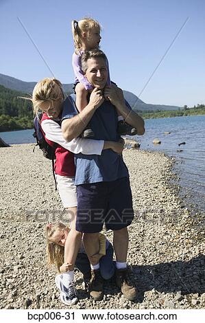 Stock Image - Family playing around next to a lake.. Fotosearch