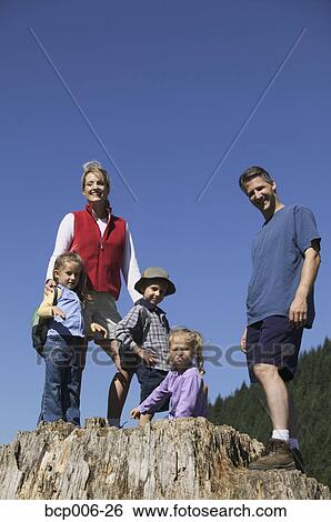 Stock Photograph - Family posing on a big tree stump.. Fotosearch