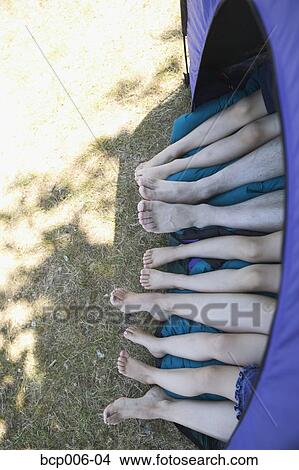 Five pairs of legs sticking out of a tent. View Large Photo Image Picture - Five pairs of legs sticking out of a tent.. Fotosearch