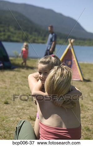 Stock Photo - Mother and daughter hugging at campsite by a lake.. Fotosearch