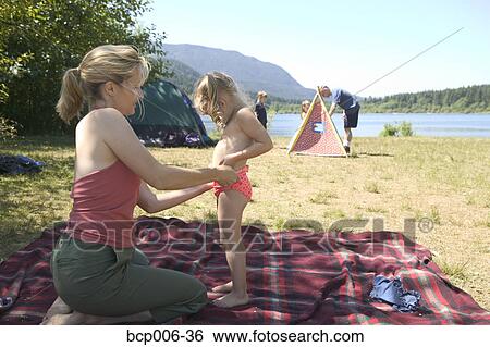 Stock Photograph - Mother changing daughter's clothing at a campsite.. Fotosearch