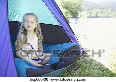 Stock Photograph - Smiling young girl eating in a tent.. Fotosearch