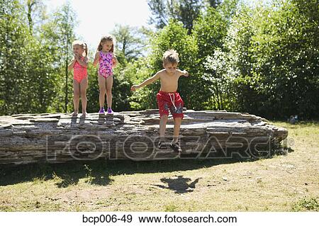 Three young children playing on a fallen log. View Large Photo Image Stock Photo - Three young children playing on a fallen log.. Fotosearch