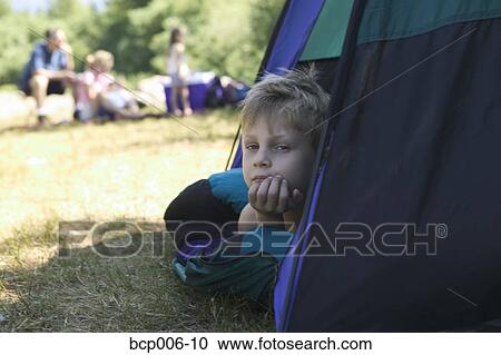 Stock Image - Young boy peeking out of tent. . Fotosearch