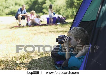Stock Image - Young camper looking through binoculars. . Fotosearch