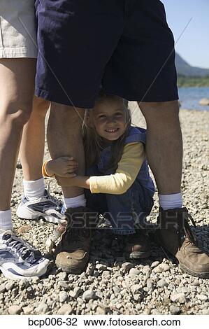 Young girl crouched between dad's legs. View Large Photo Image Stock Image - Young girl crouched between dad's legs.. Fotosearch
