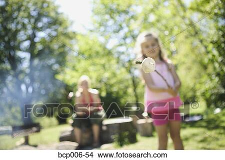 Picture - Young girl roasting a marshmallow.. Fotosearch