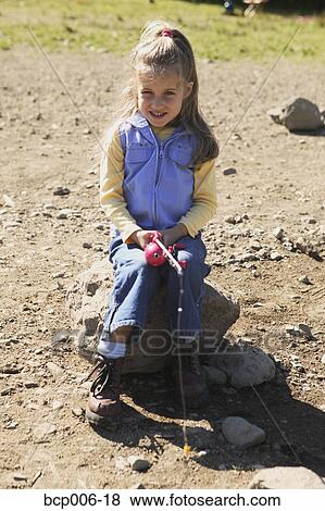 Young girl sitting on a rock and fishing. View Large Photo Image Stock Photo - Young girl sitting on a rock and fishing.. Fotosearch