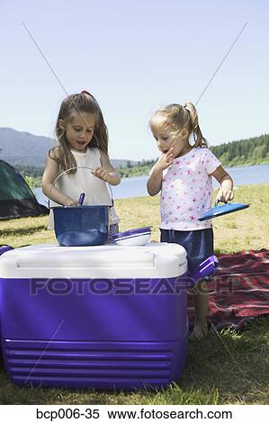 Young sisters preparing food on a cooler at a campsite. View Large Photo Image Stock Photography - Young sisters preparing food on a cooler at a campsite.. Fotosearch