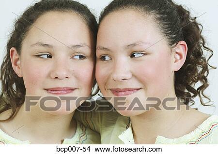 Close-up portrait of teenage twin girls, looking at each other. View Large Photo Image Picture - Close-up portrait of teenage twin girls, looking at each other.. Fotosearch