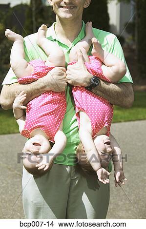 Father holding his twin babies upside down. View Large Photo Image Picture - Father holding his twin babies upside down.. Fotosearch