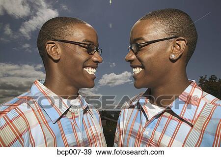 Outdoors portrait of twin African-American teenage boys in glasses and matching plaid shirts. View Large Photo Image Stock Photo - Outdoors portrait of twin African-American teenage boys in glasses and matching plaid shirts.. Fotosearch