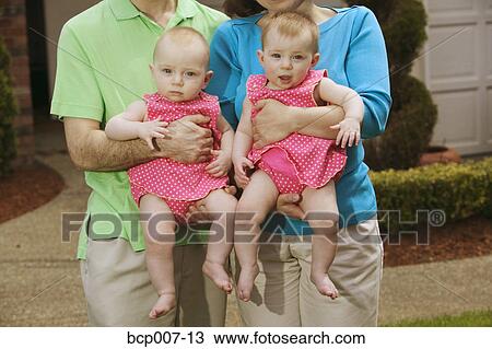 Twin babies held in their parents' arms. View Large Photo Image Stock Image - Twin babies held in their parents' arms.. Fotosearch