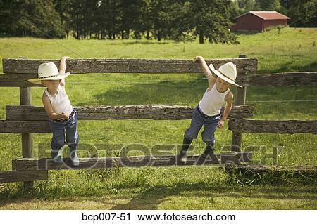 Twin boys in cowboy hats hanging on a fence. View Large Photo Image Stock Image - Twin boys in cowboy hats hanging on a fence.. Fotosearch