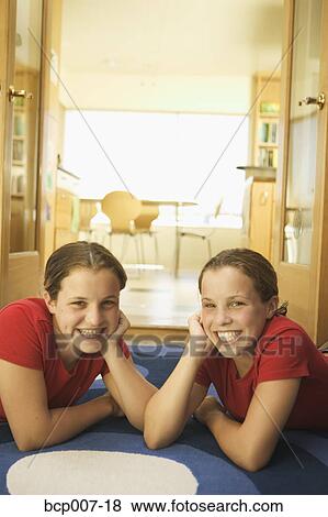 Twin Caucasian teenage girls lounging on a rug. View Large Photo Image Stock Photo - Twin Caucasian teenage girls lounging on a rug.. Fotosearch
