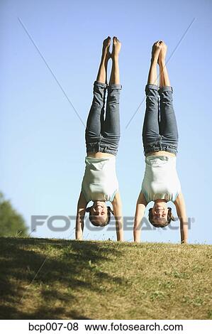 Twin Caucasian teenage girls perform side by side handstands in the park. View Large Photo Image Stock Photo - Twin Caucasian teenage girls perform side by side handstands in the park.. Fotosearch